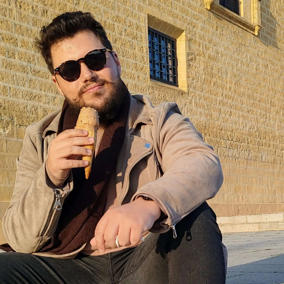 Hombre con gafas de sol redondas de carey y cristales marrones polarizados, vistiendo chaqueta beige con helado.
