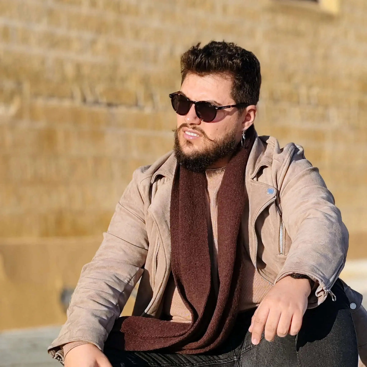 Hombre con gafas de sol redondas de carey, montura efecto tortuga y lentes polarizadas marrones, estilo casual otoñal.