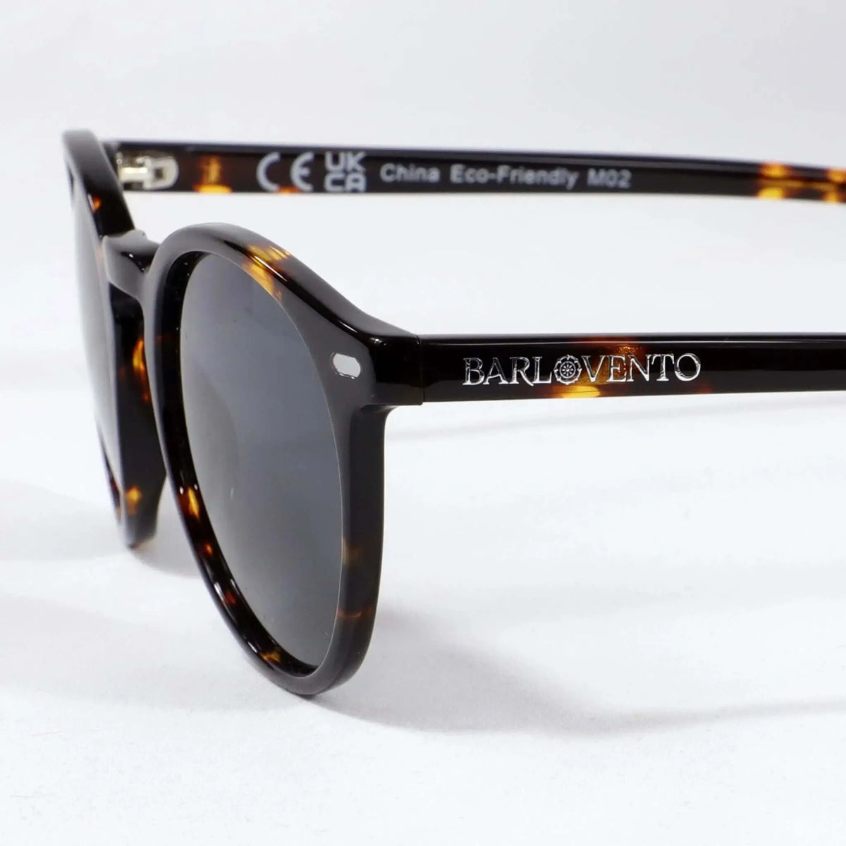 Gafas de sol redondas de carey con montura brillante y lentes polarizadas oscuras sobre fondo blanco. Estilo clásico.