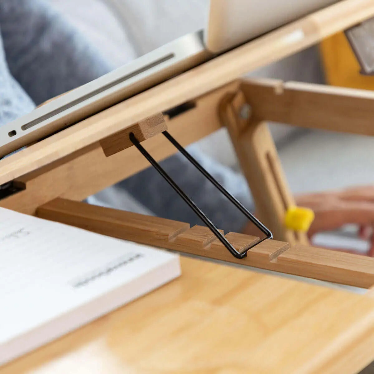 Mesa auxiliar de bambú para portátil con soporte ajustable y superficie inclinable de madera clara.