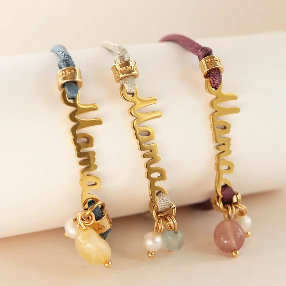 Pulsera "Mama" dorada con cuentas de piedras preciosas, disponible en azul, gris y púrpura, estilo moderno y elegante.