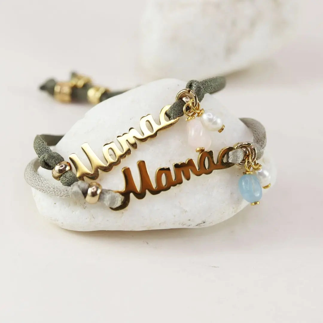 Pulsera "Mamá" dorada en metal con cuentas de perlas y piedras, cordón verde oliva, estilo moderno y elegante.