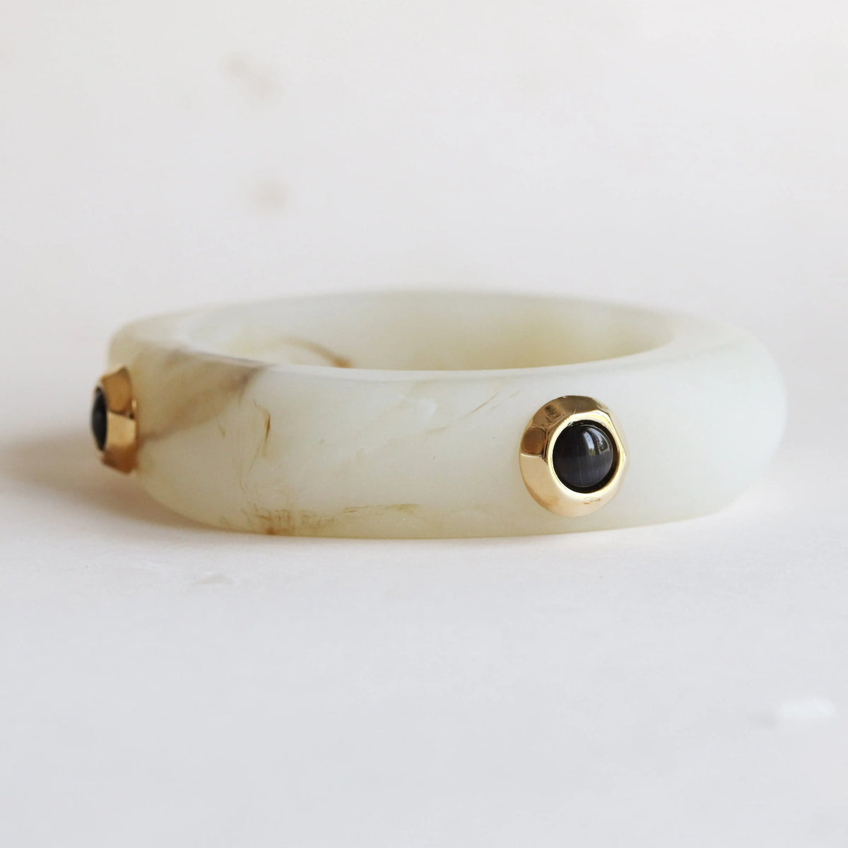 Brazalete de resina verde claro con detalles en oro y gemas negras, estilo moderno y elegante.