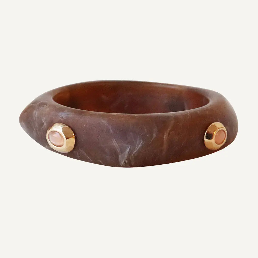 Brazalete de resina marrón con detalles dorados y piedras rosas, estilo moderno y elegante.