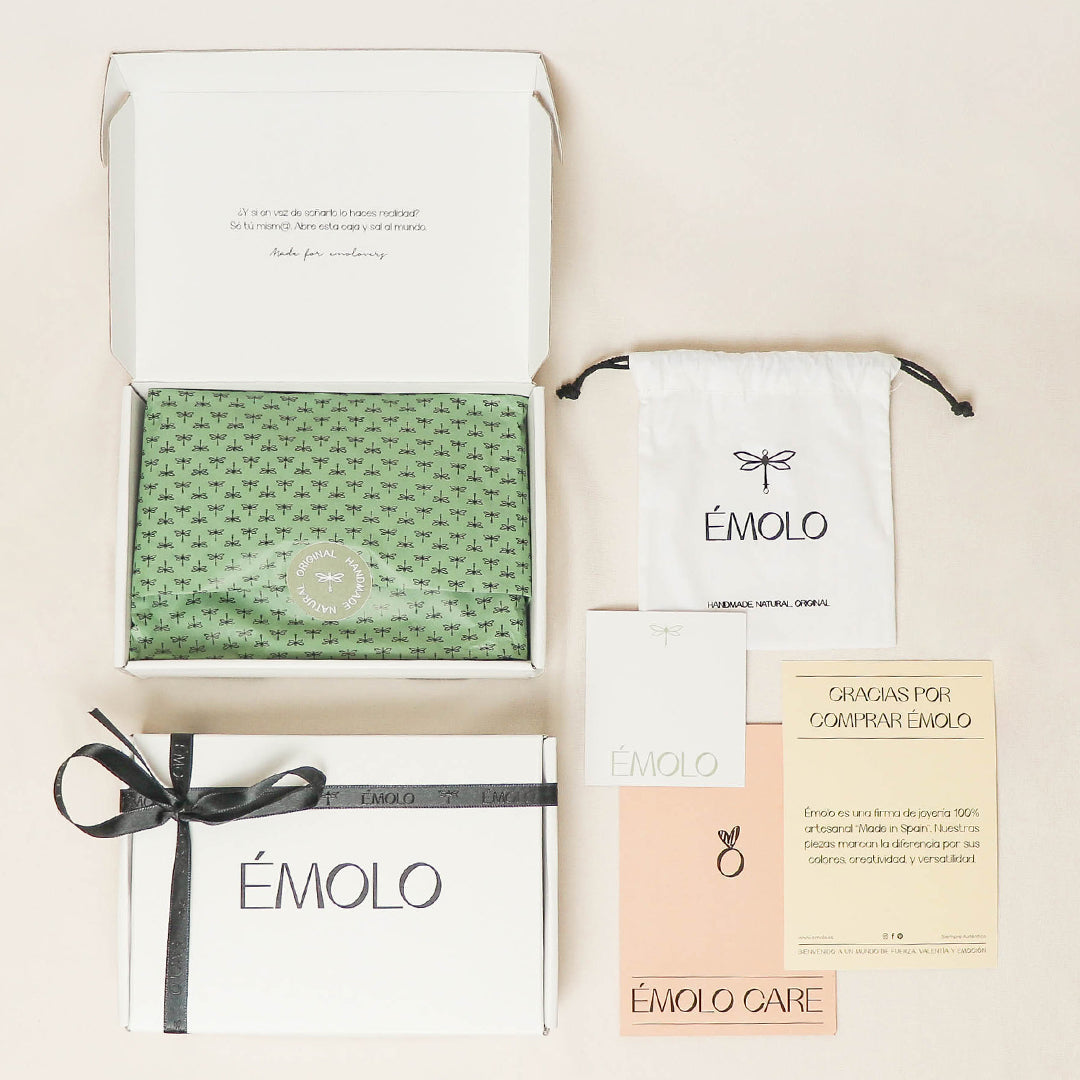 Caja de regalo Émolo con papel verde estampado, bolsa blanca, tarjeta de agradecimiento y mensaje de cuidado.