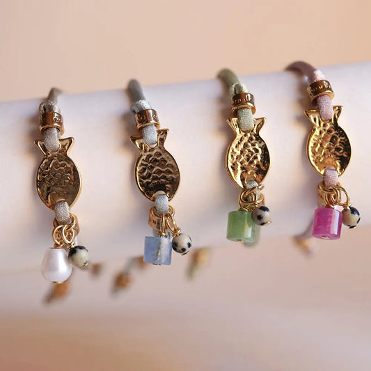 Pulseras de colores pastel con adornos dorados y piedras naturales, estilo bohemio y elegante.