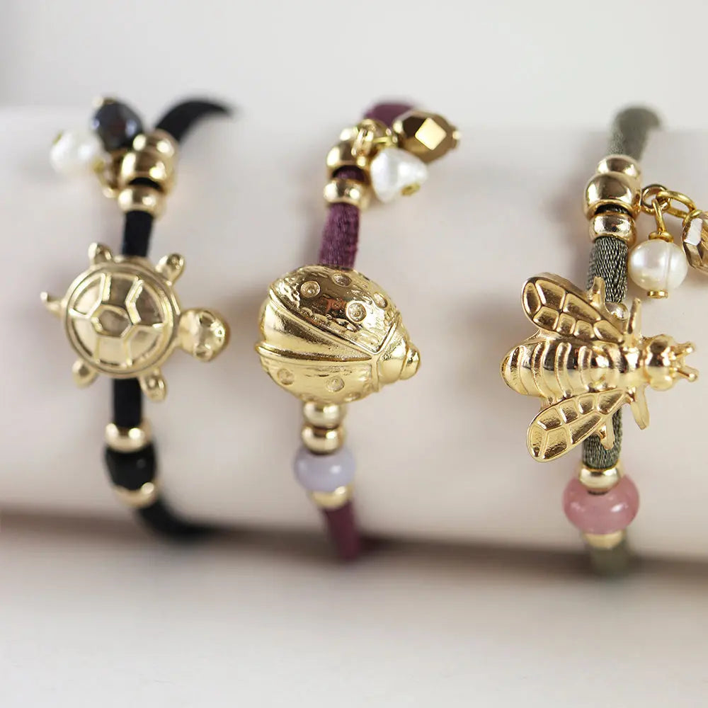 Pulseras de cuerda en tonos negro, burdeos y gris con charm de tortuga, mariquita y abeja en dorado.