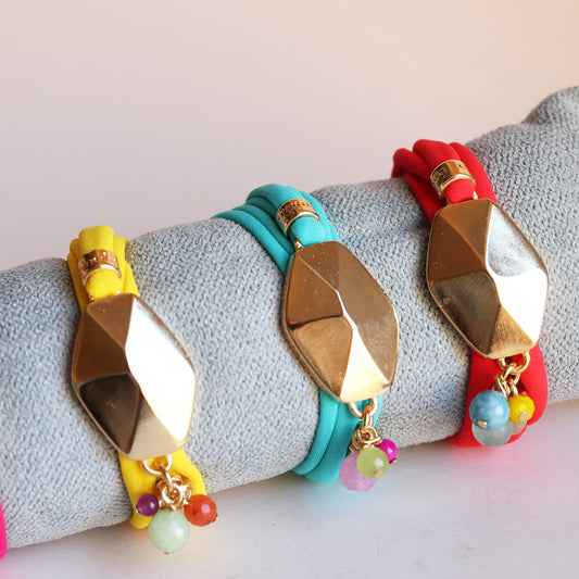 Pulseras de colores amarillo, azul y rojo con detalles dorados y cuentas de piedras, estilo moderno y vibrante.
