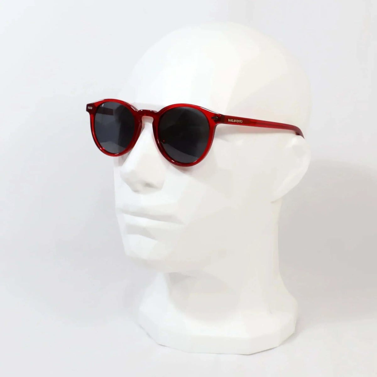 Gafas de sol redondas con montura de acetato rojo brillante y cristales oscuros sobre maniquí blanco.
