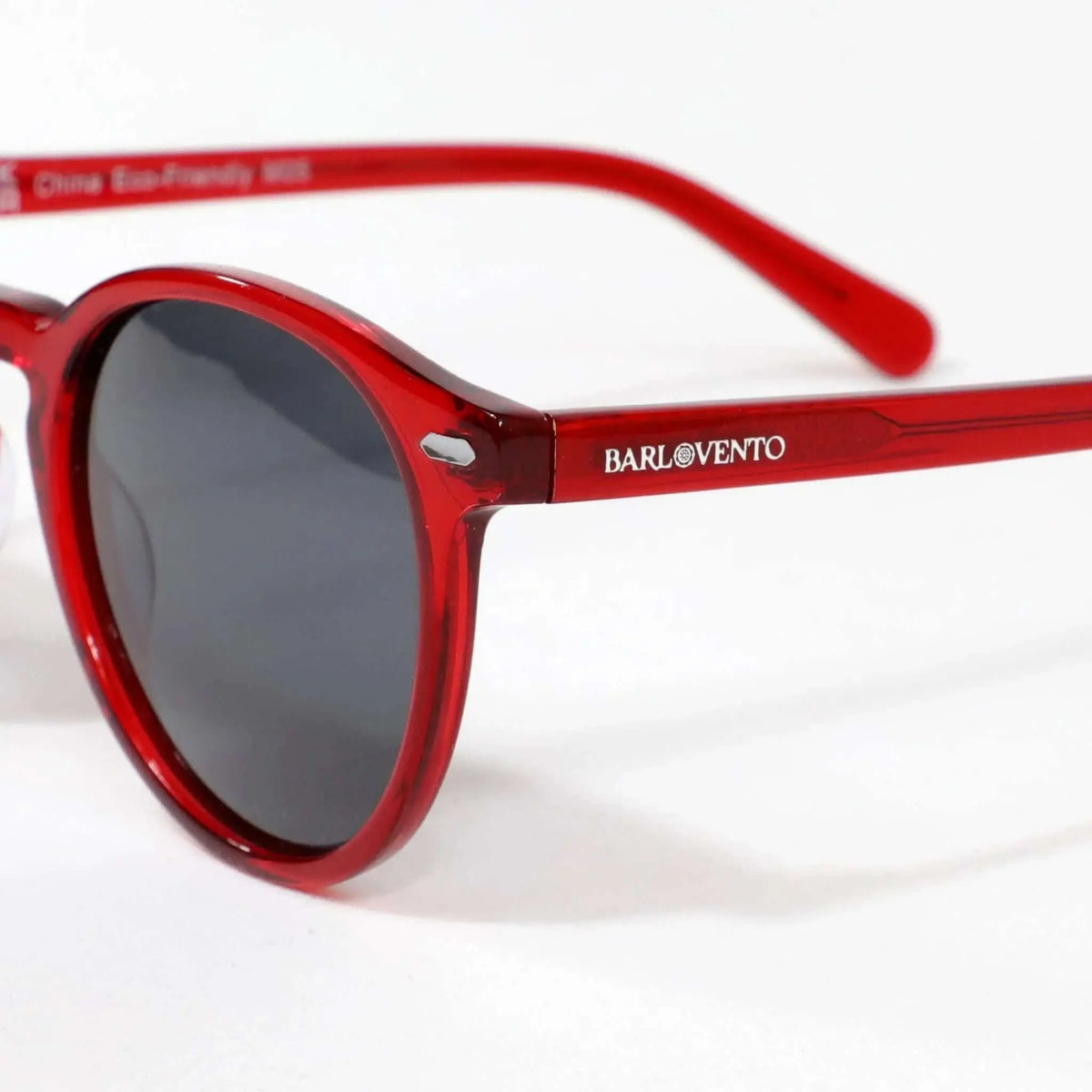 Gafas de sol redondas con montura de acetato rojo translúcido y cristales oscuros, estilo moderno y minimalista.