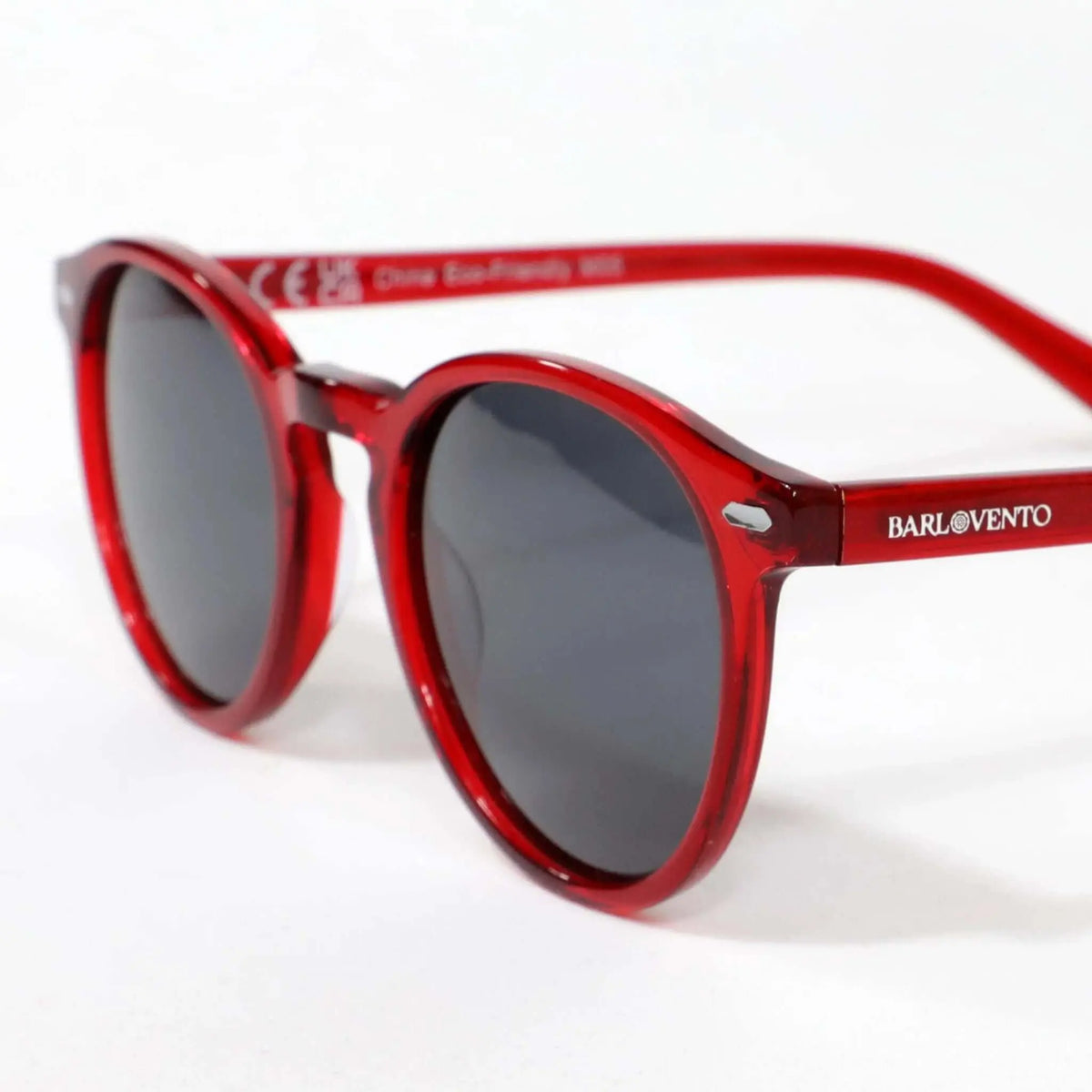 Gafas de sol redondas con montura de acetato rojo traslúcido y cristales oscuros, estilo moderno y diseño casual.