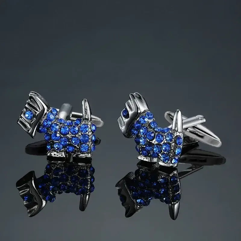 Gemelos metálicos con forma de perro terrier cubiertos de cristales brillantes color azul sobre fondo oscuro.