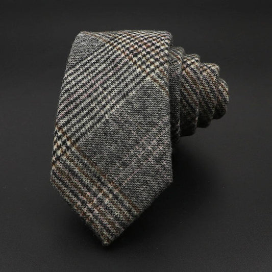 Corbata de lana gris con estampado de cuadros estilo tweed, textura tejida y acabado elegante sobre fondo negro.