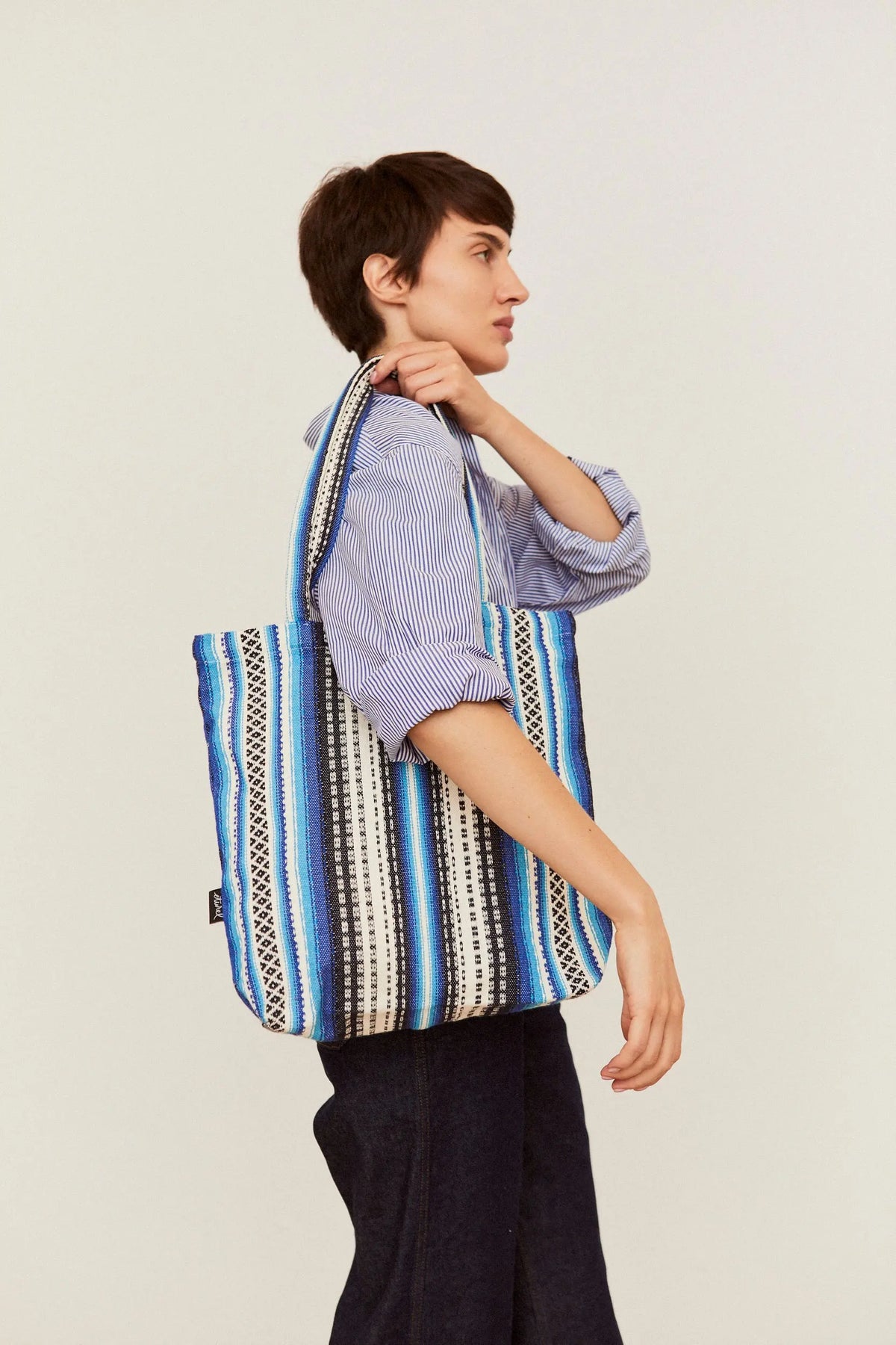 Tote bag de tela con estampado alpujarra en tonos azules y blancos, de estilo artesanal, colgada al hombro.