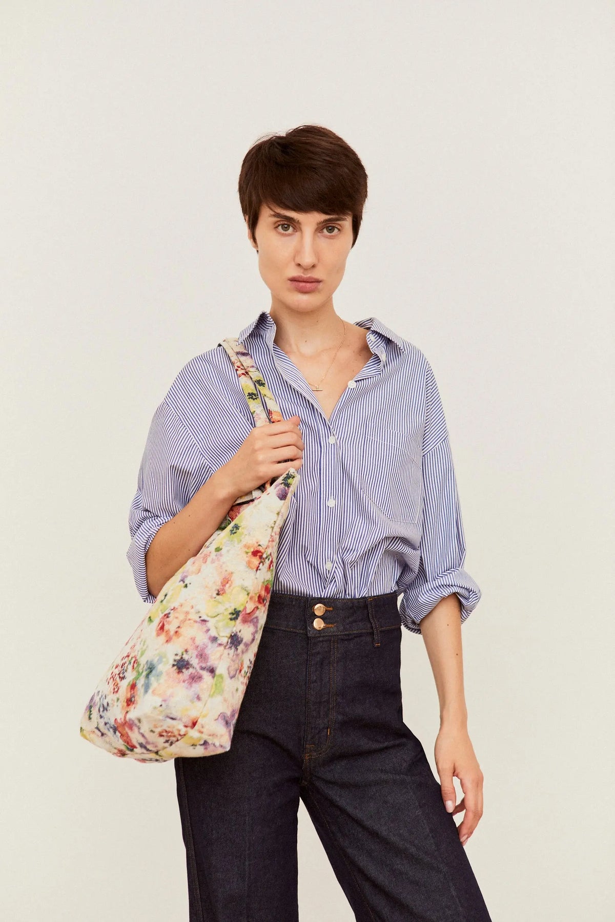 Tote bag de tejido jacquard con estampado de flores amapolas coloridas sobre fondo claro, llevado al hombro.
