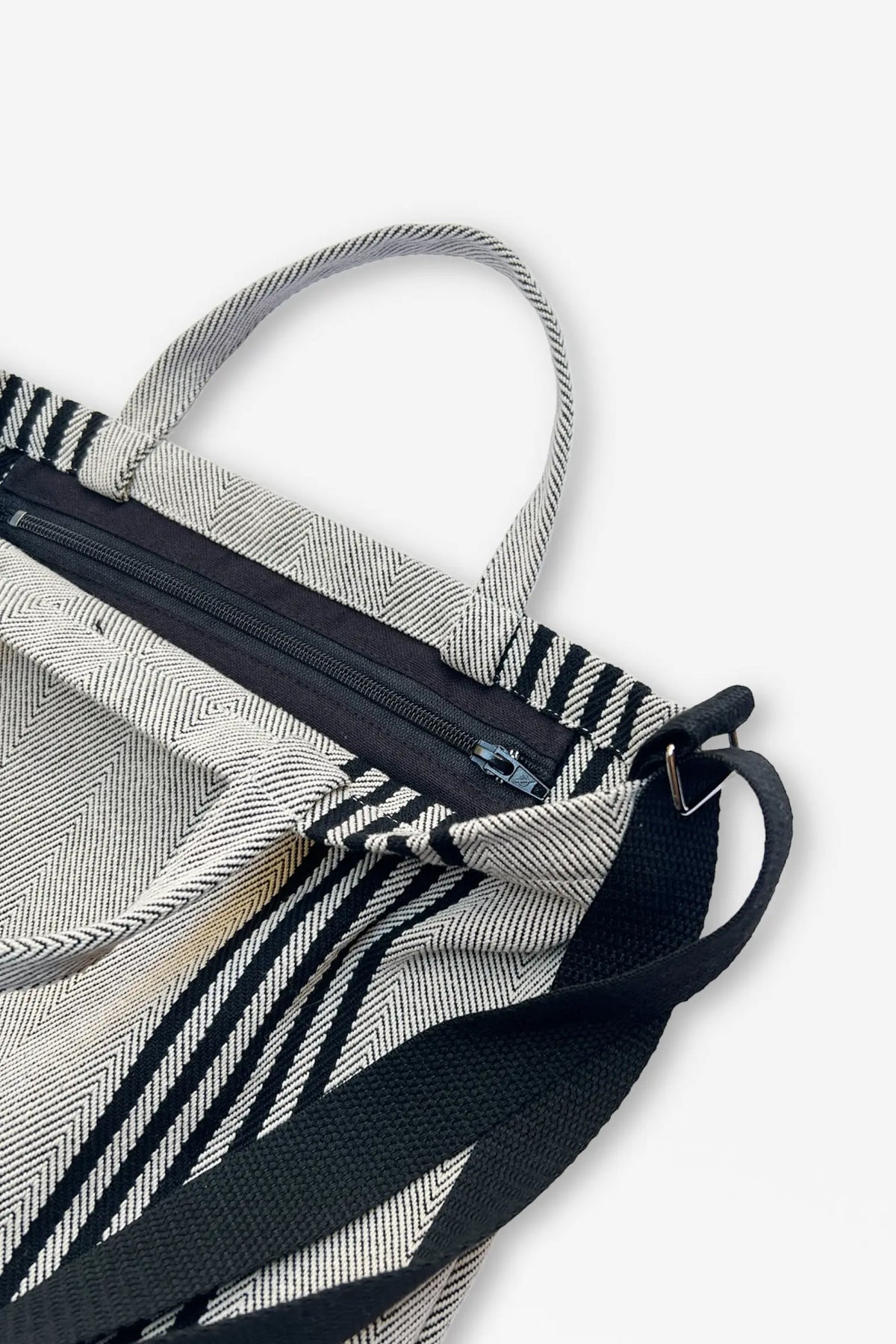 Bolso bandolera de sarga con estampado de espiga en blanco y negro, cierre de cremallera y correas ajustables negras.