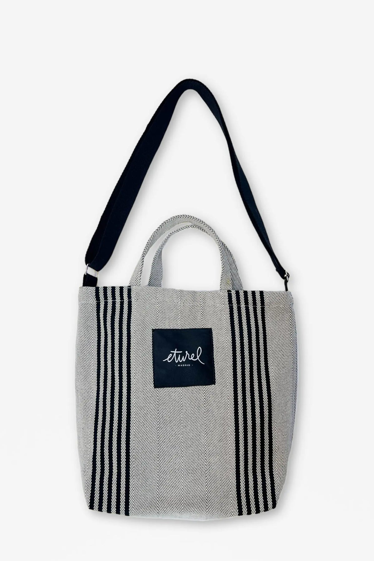 Bolso bandolera de sarga en color crema y negro, con tejido en espiga, asas cortas y correa ajustable para el hombro.