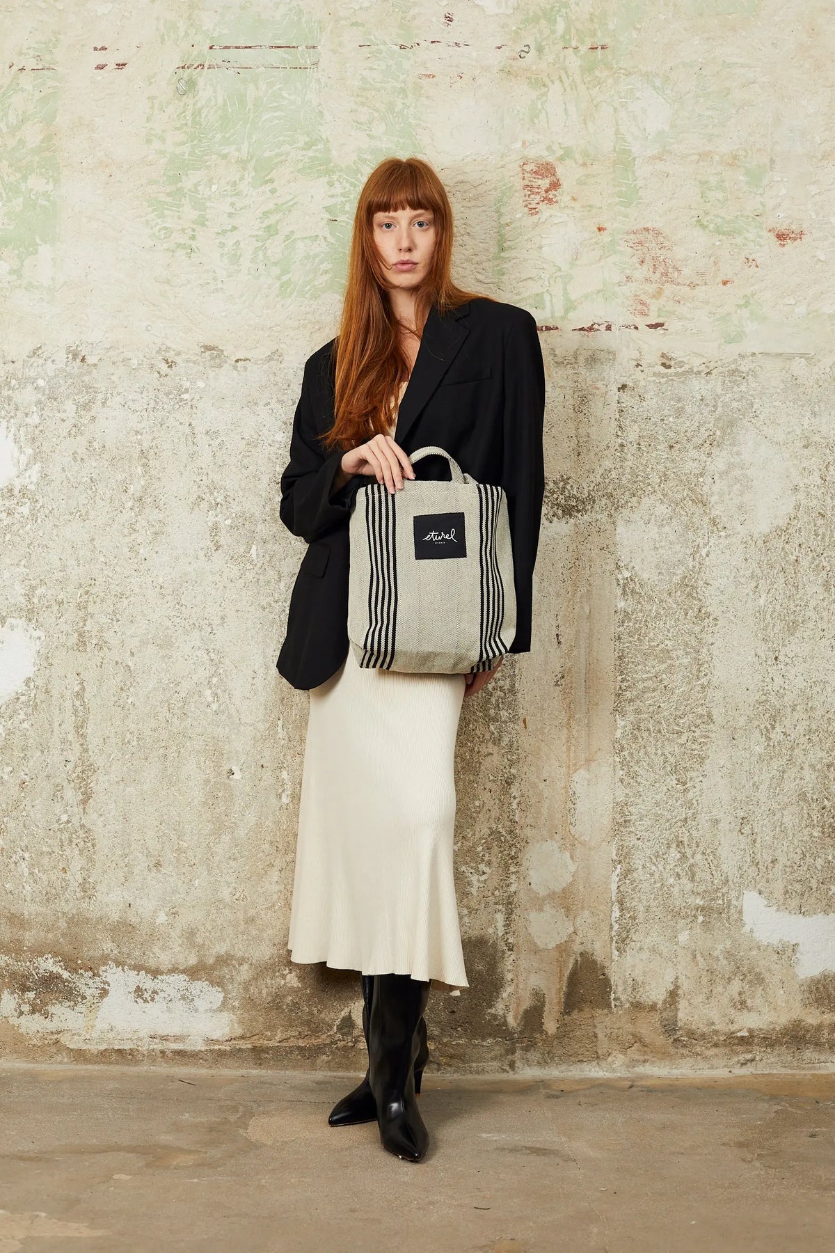 Bolso bandolera tipo tote en sarga beige con rayas negras verticales, diseño casual y elegante de tela resistente.