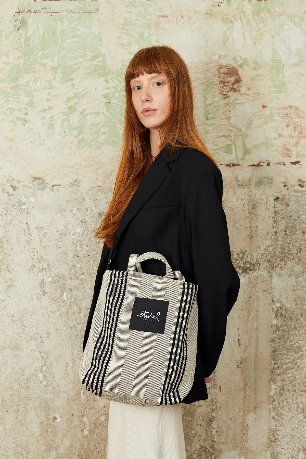 Bolso bandolera de sarga en color beige con rayas verticales negras, estilo casual con asas cortas y correa ajustable.