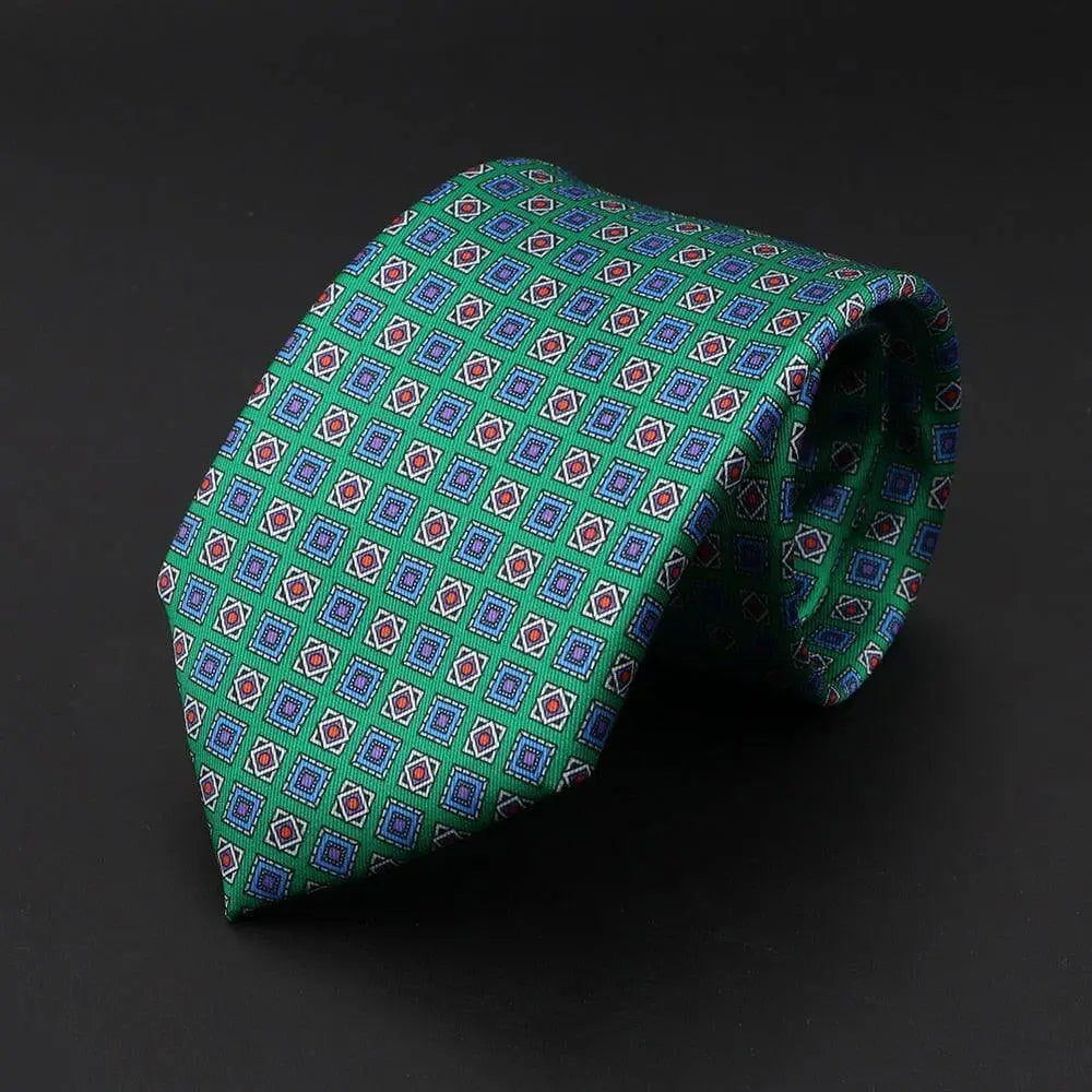 Corbata de seda verde con estampado geométrico de rombos y cuadrados en tonos azules y rojos, estilo elegante italiano.