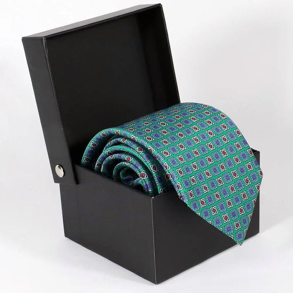 Corbata de seda verde con estampado geométrico azul y detalles en rojo, presentada en una caja de regalo negra abierta.