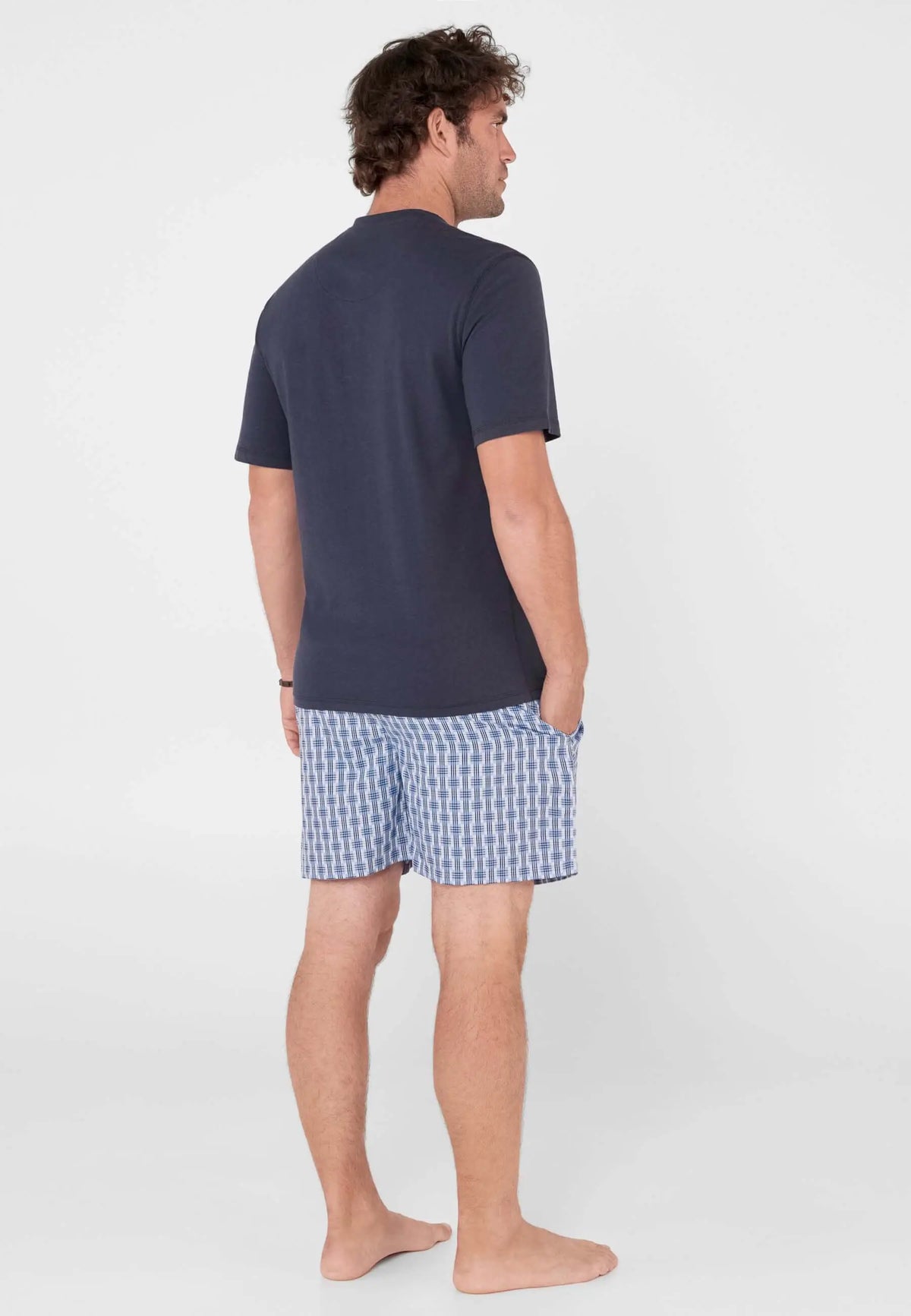 Pijama corto de hombre: camiseta lisa azul marino de manga corta y pantalón corto con estampado de cuadros azules.