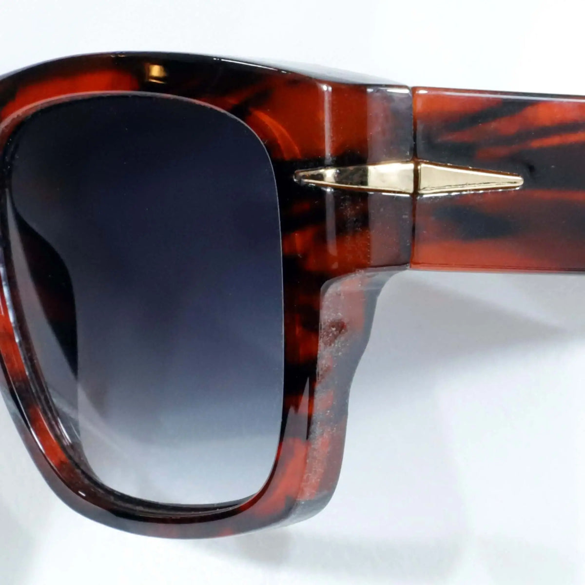 Gafas de sol carey con montura brillante y detalle metálico dorado, lentes azules con protección UV400. Estilo clásico.