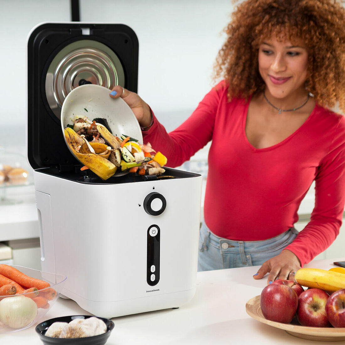 Mujer usando compostador eléctrico de cocina Ewooster añadiendo residuos orgánicos de frutas y verduras