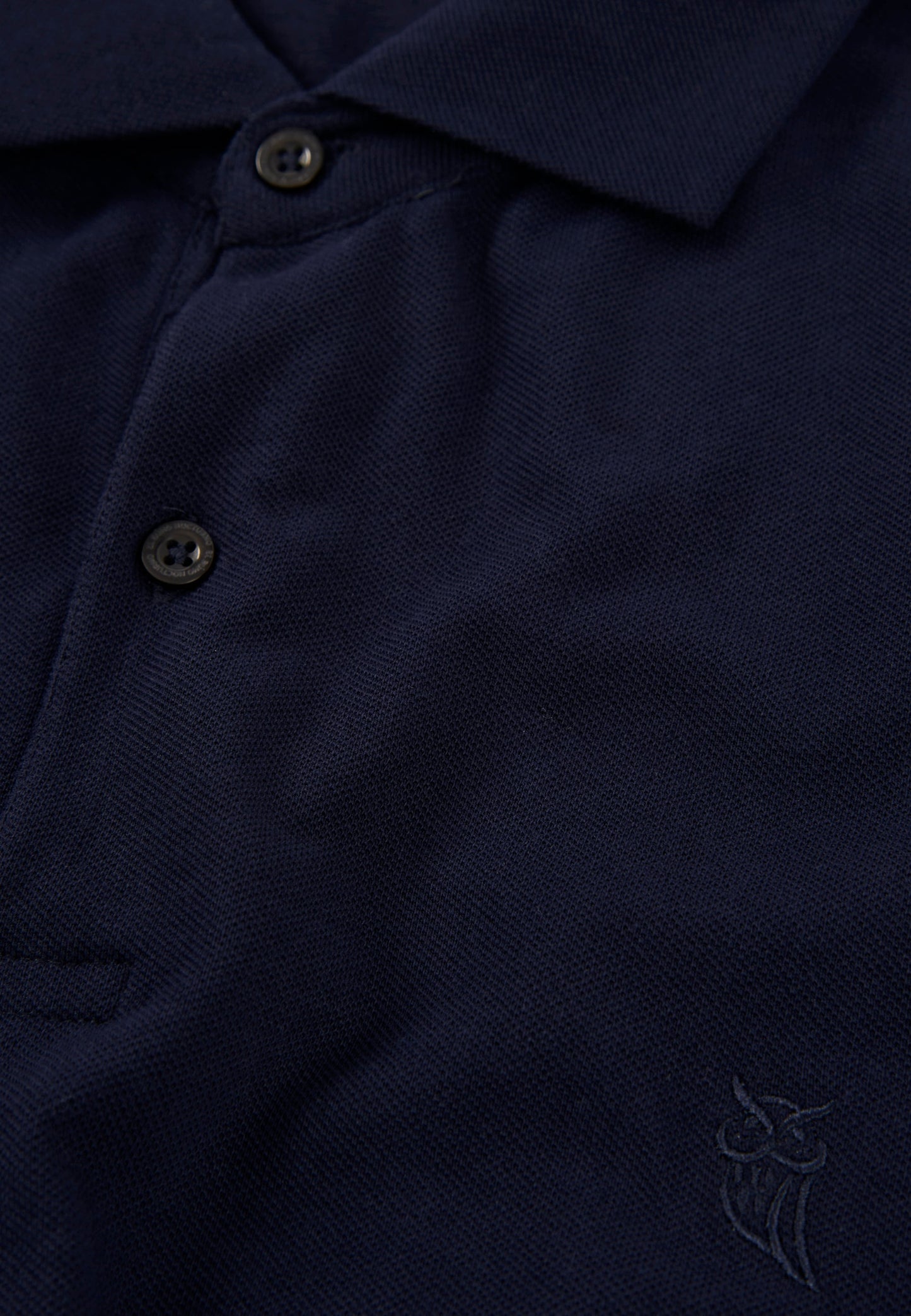 Polo azul marino de algodón con botones, estilo clásico y logo bordado en el pecho.