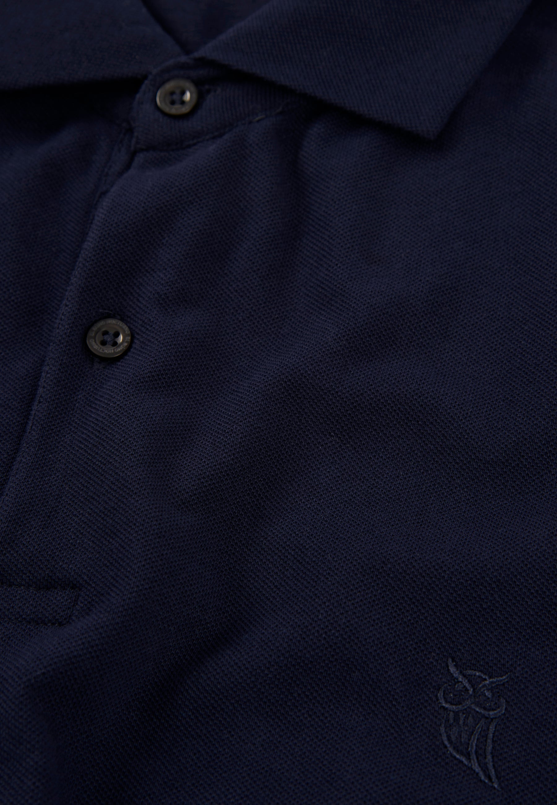 Polo azul marino de algodón con botones, estilo clásico y logo bordado en el pecho.