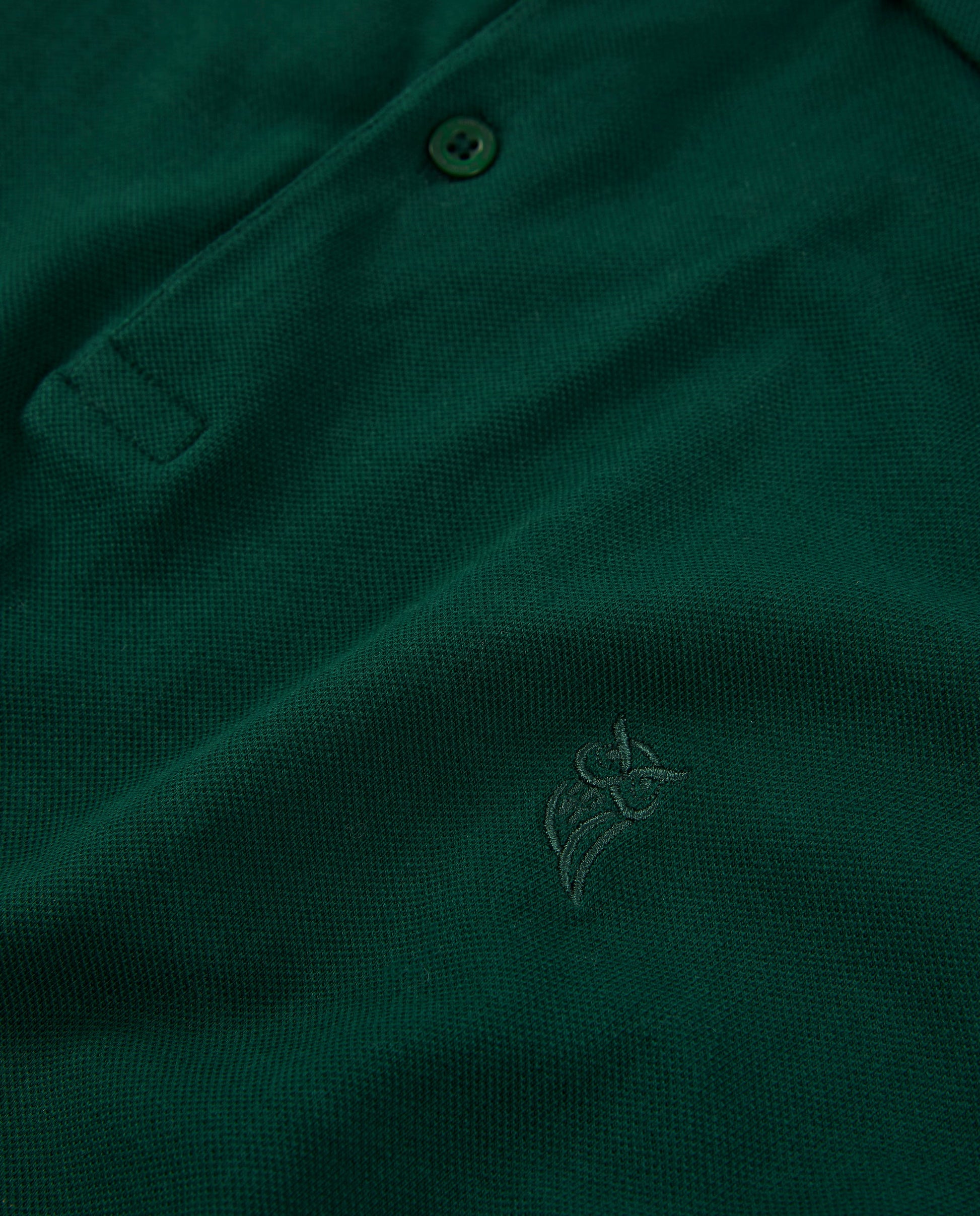 Polo de hombre verde oscuro, tejido de piqué, con bordado discreto y botones en la parte delantera.