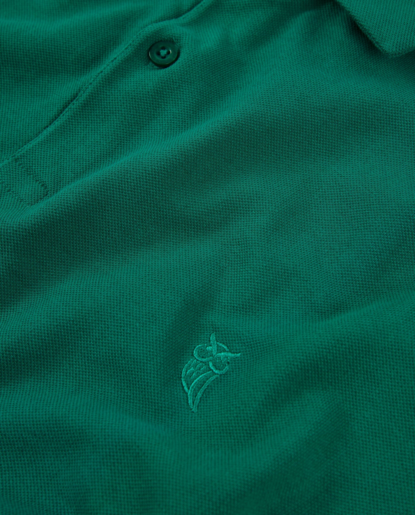 Polo verde de algodón con diseño bordado en tono a juego, estilo clásico y elegante.