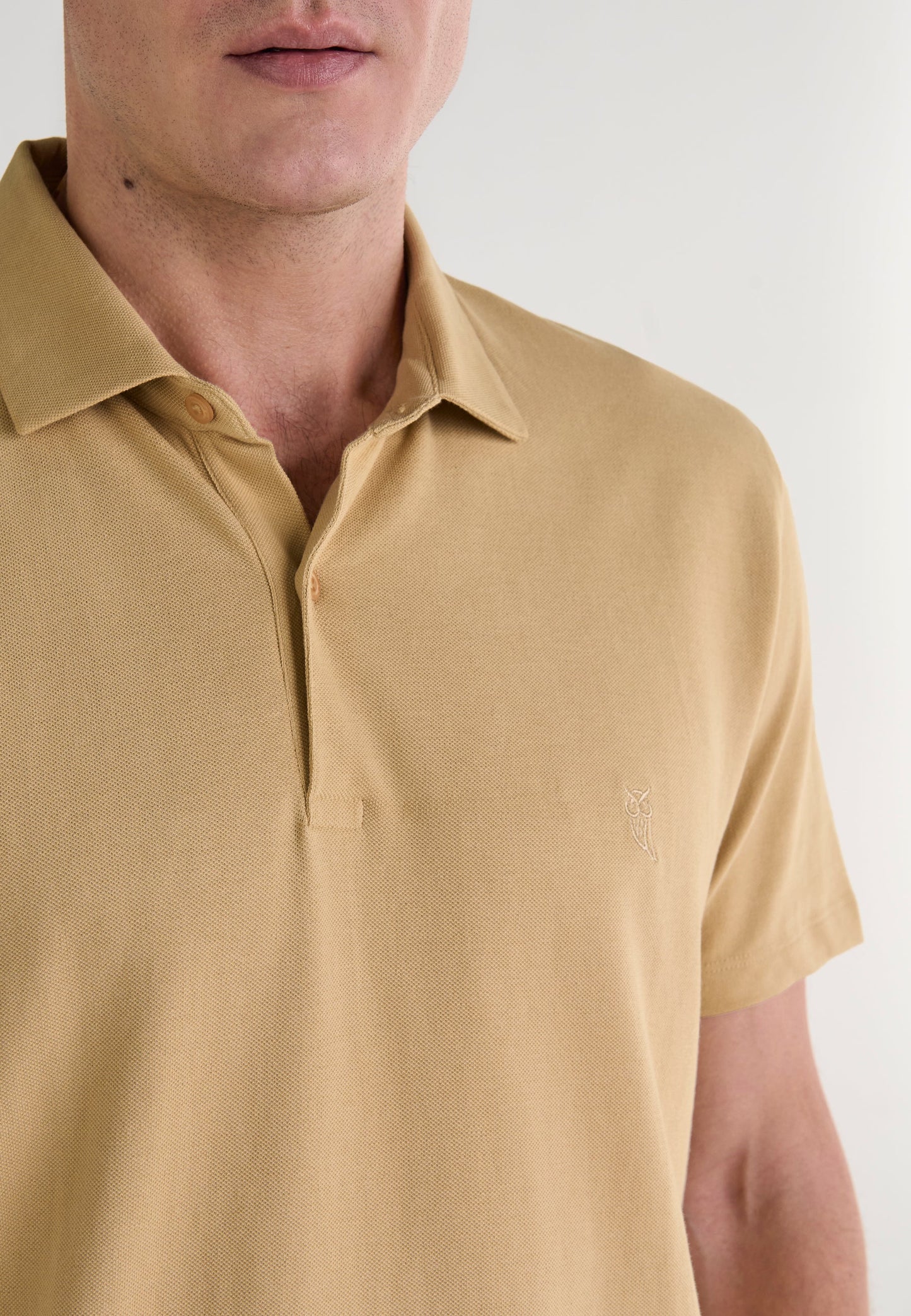 Polo de hombre color mostaza de algodón, con cuello clásico y logo bordado en el lado izquierdo del pecho.
