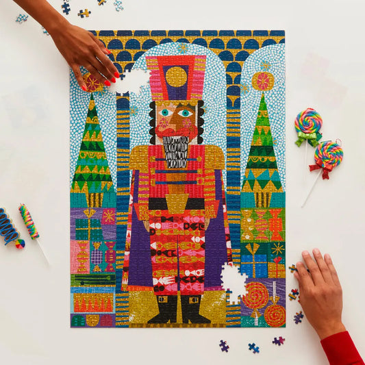 A 1000-piece jigsaw puzzle featuring a vibrant, stylized nutcracker in festive colors with gold foil accents.