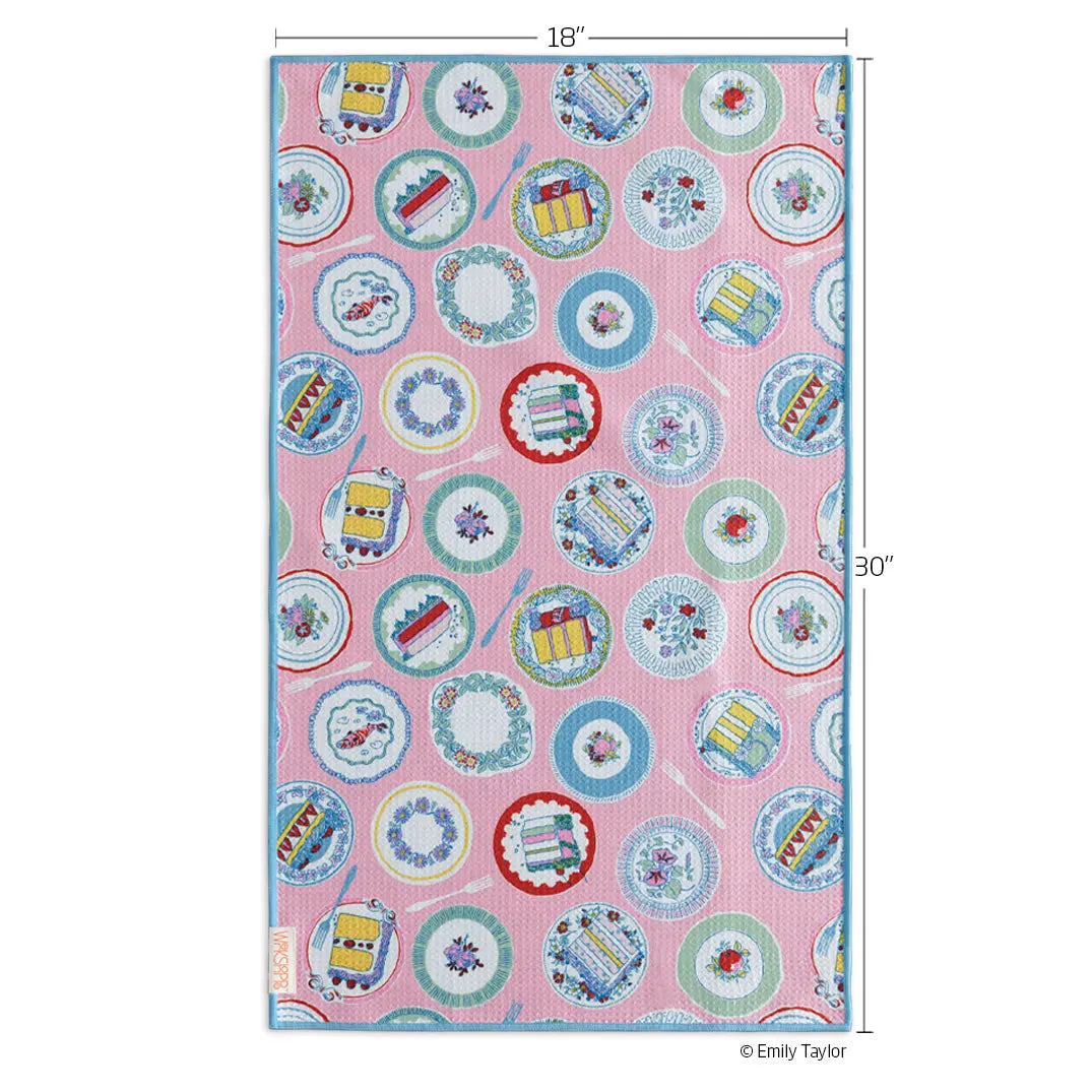 Pink microfiber towel with a repeating pattern of cake slices, decorative plates, and forks, measuring 18" by 30".