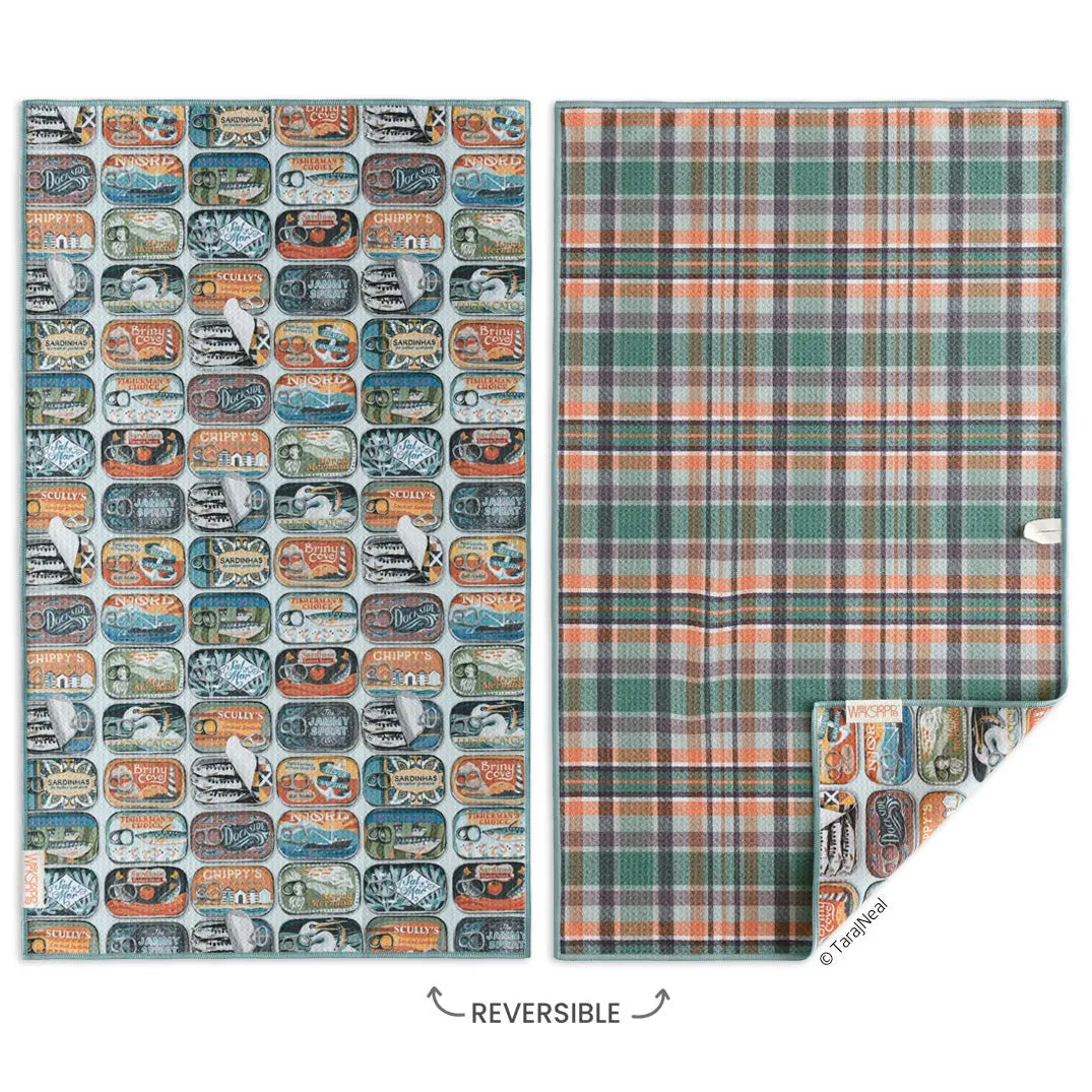 Reversible microfiber towel featuring a pattern of vintage sardine tins on one side and green and orange plaid reverse.