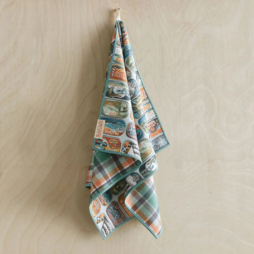 Microfiber towel with a vintage sardine can print on one side and a teal and orange plaid pattern on the other.