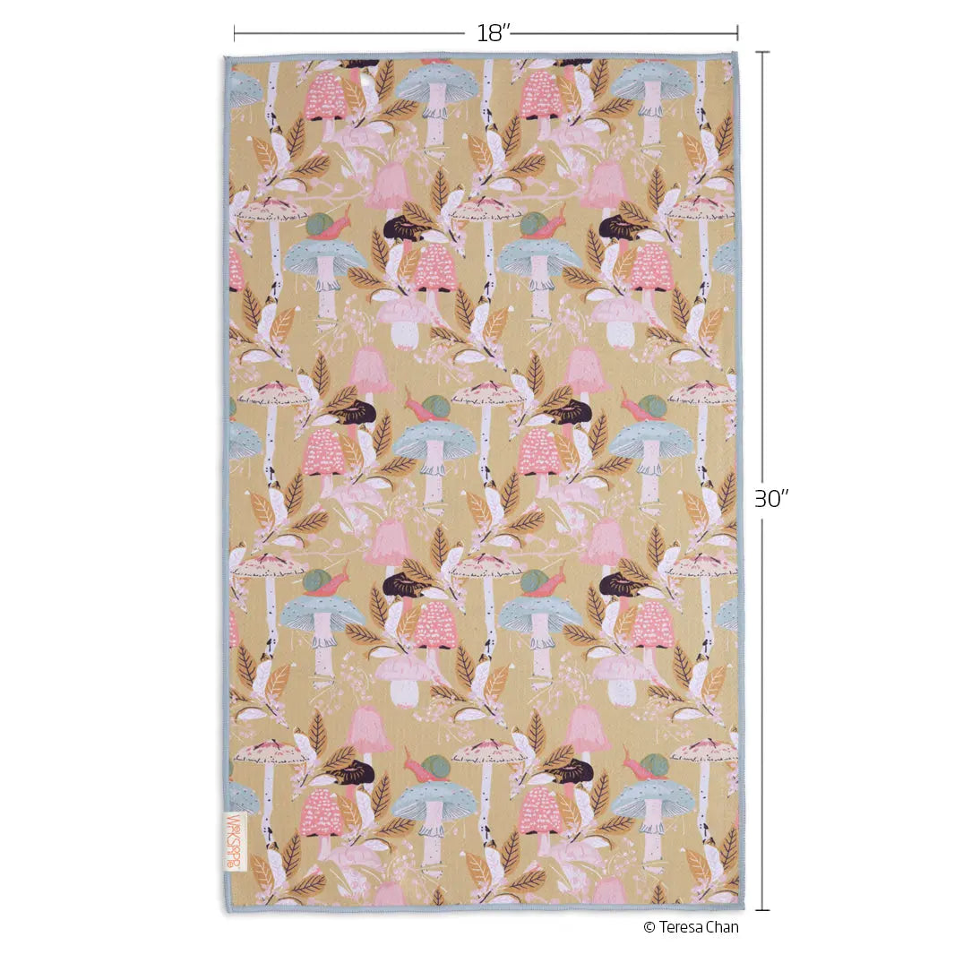 Microfiber kitchen towel with a repeating pattern of pink and blue woodland mushrooms, foliage, and snails on tan.