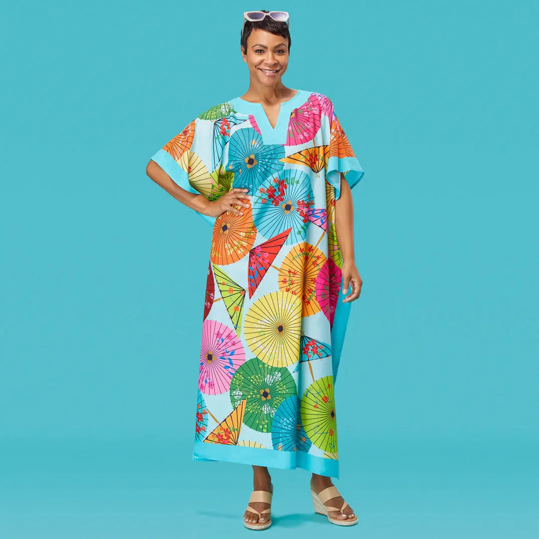 Woman wearing a loose light blue caftan featuring a colorful, vibrant print of open parasols.