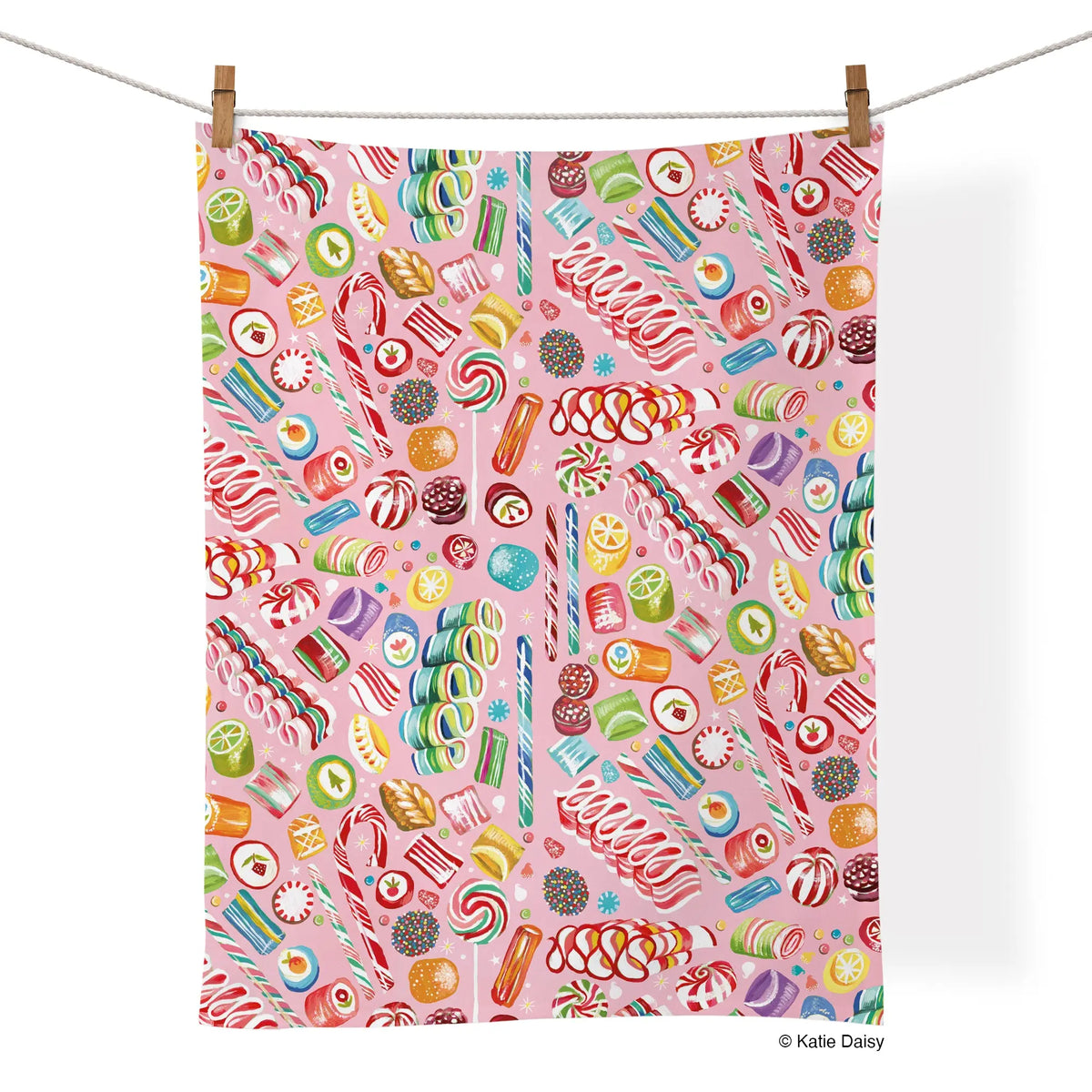 Cotton tea towel with a pink background featuring a pattern of colorful festive holiday candies and sweets.