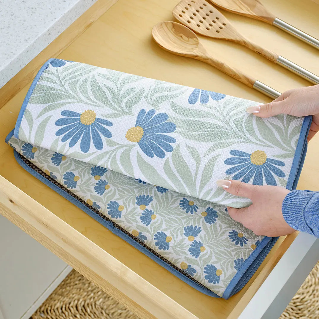 Folding dish mat with blue and yellow coneflower pattern, light green foliage, and blue trim.
