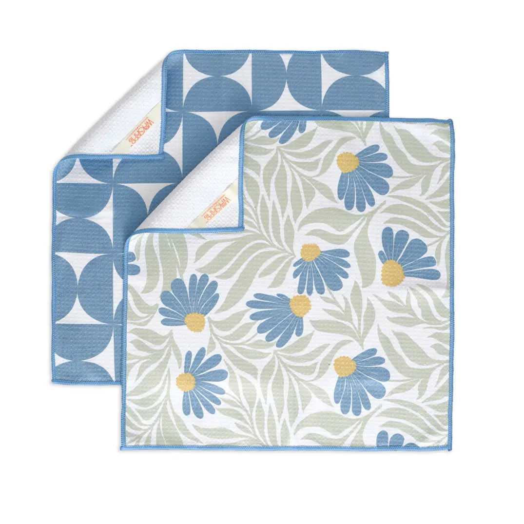 Two folded towels with textured fabric: one with blue geometric semicircles, the other with blue coneflower print.