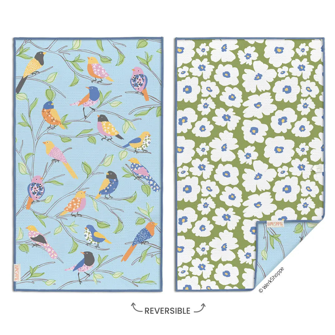 Reversible microfiber towel featuring a blue bird and branch pattern on one side and a white floral print on green.