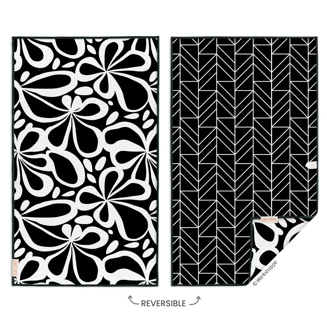 Reversible microfiber towel featuring a bold black and white floral pattern on one side and a geometric print on back.