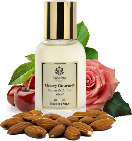 Cherry Gourmet perfume bottle with gold cap, surrounded by fresh cherries, a pink rose, and scattered almonds.