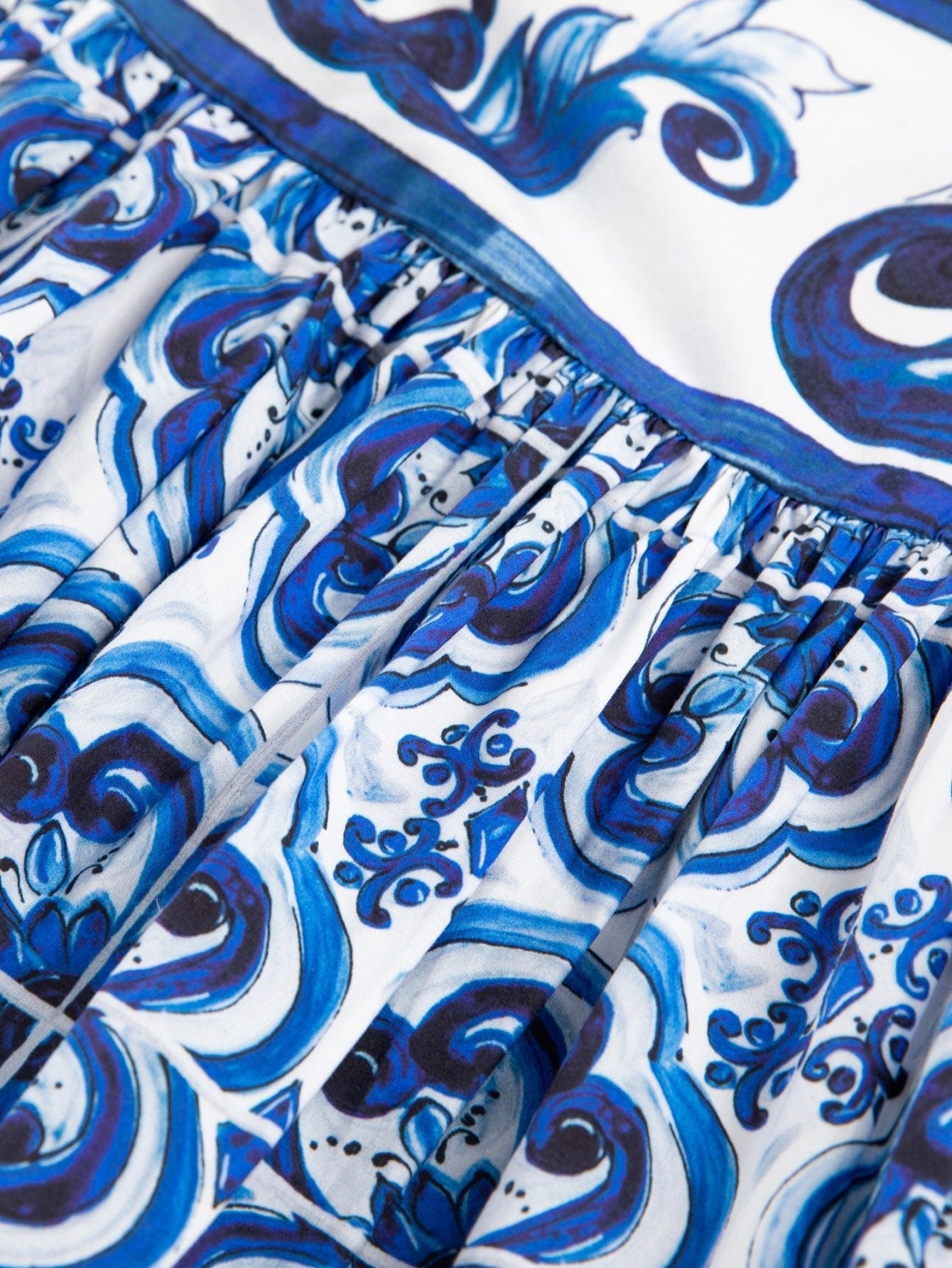 Pleated cotton skirt featuring a white and blue Majolica-style porcelain tile print with intricate swirling patterns.