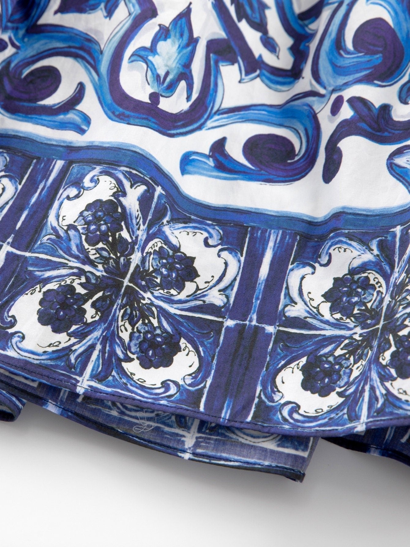 Close-up of a 100% cotton skirt featuring a blue and white Majolica porcelain tile print with ornate floral motifs.