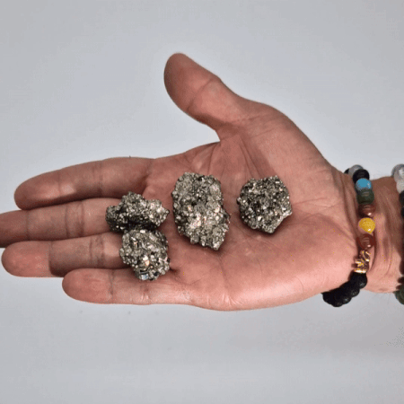 Piedras de pirita gris en mano, brillo metálico y texturas naturales, ideal para decoración o colecciones minerales.
