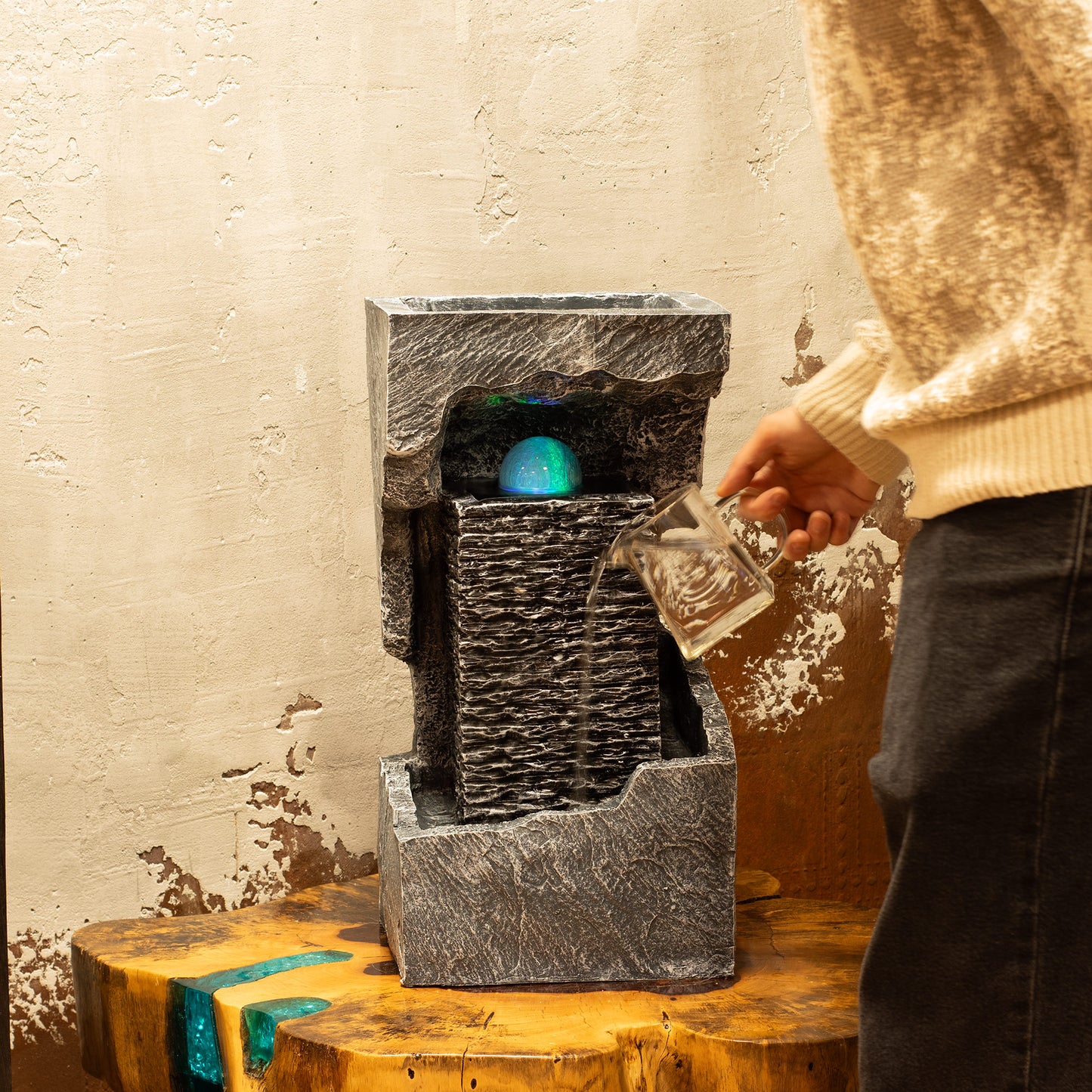 Fuente de agua de resina gris con efecto de luz azul, estilo moderno, ideal para interior o exterior.