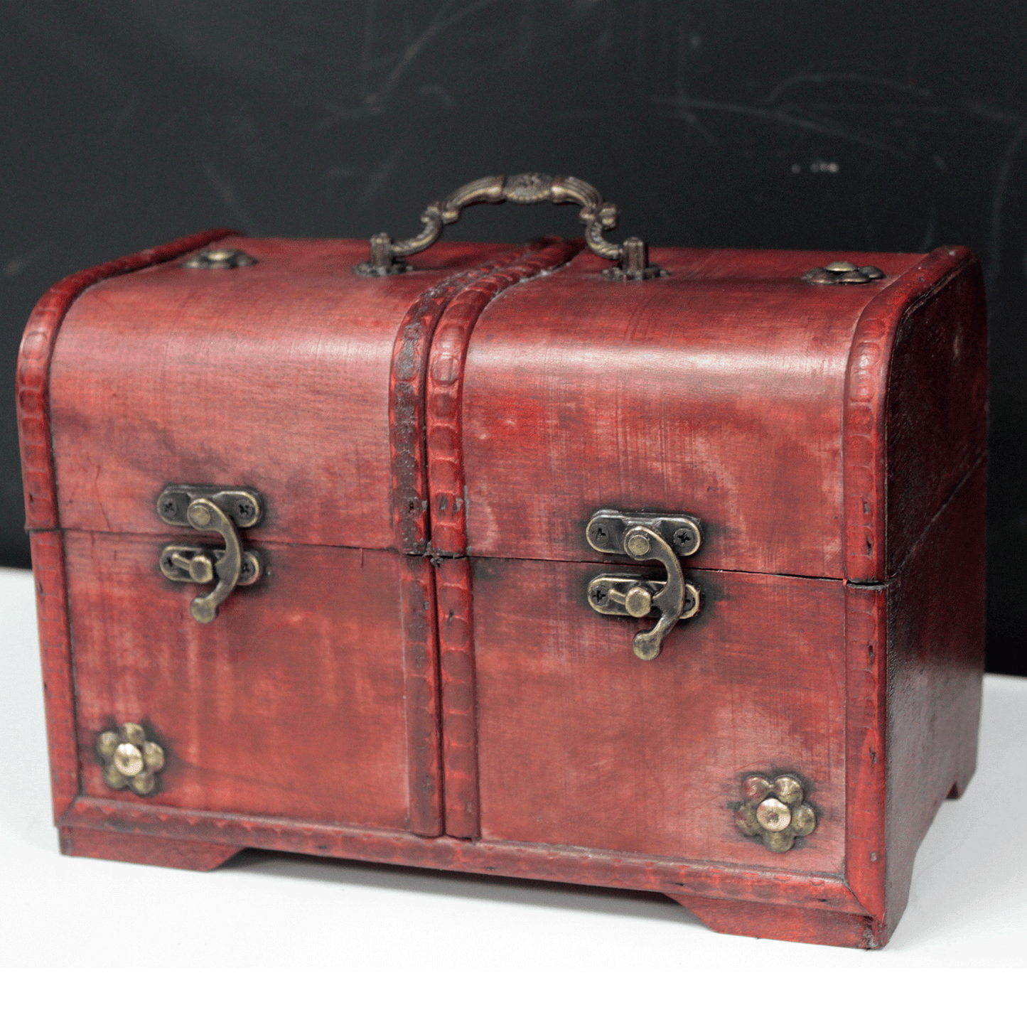 Caja de madera roja vintage con herrajes dorados y detalle de costura, ideal para decoración o almacenamiento.
